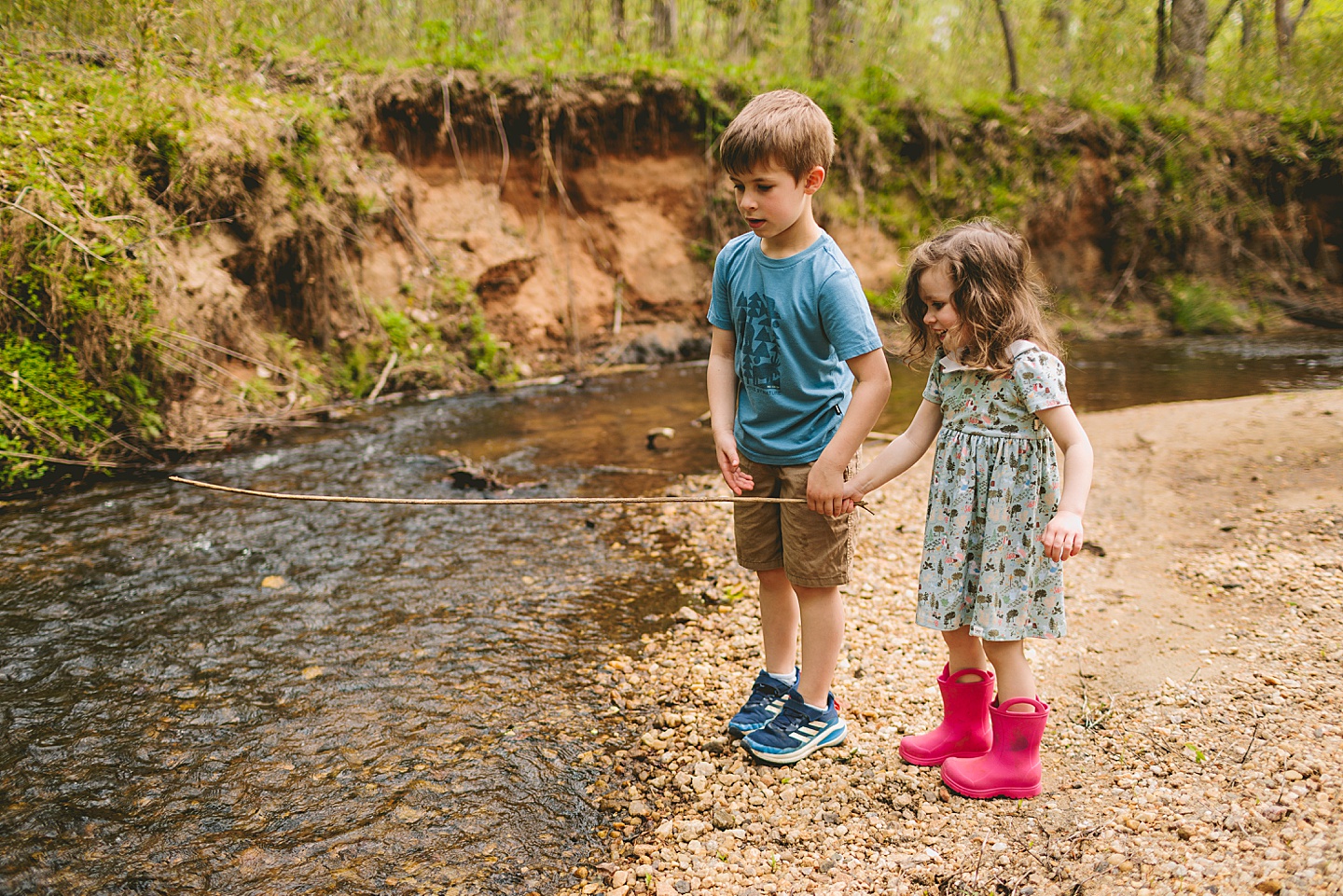 Brother and sister go fishing in a creek with a stick