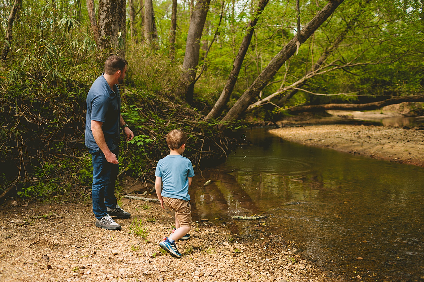 Father teaching son to skip stones in creek