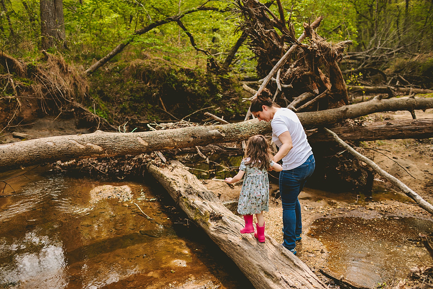 Mom helping daughter walk across a log