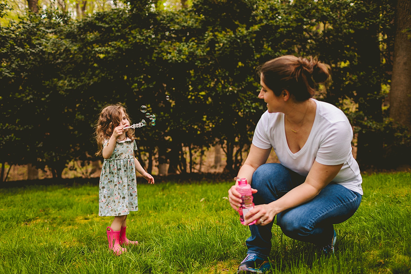 Girl blowing bubbles with mom