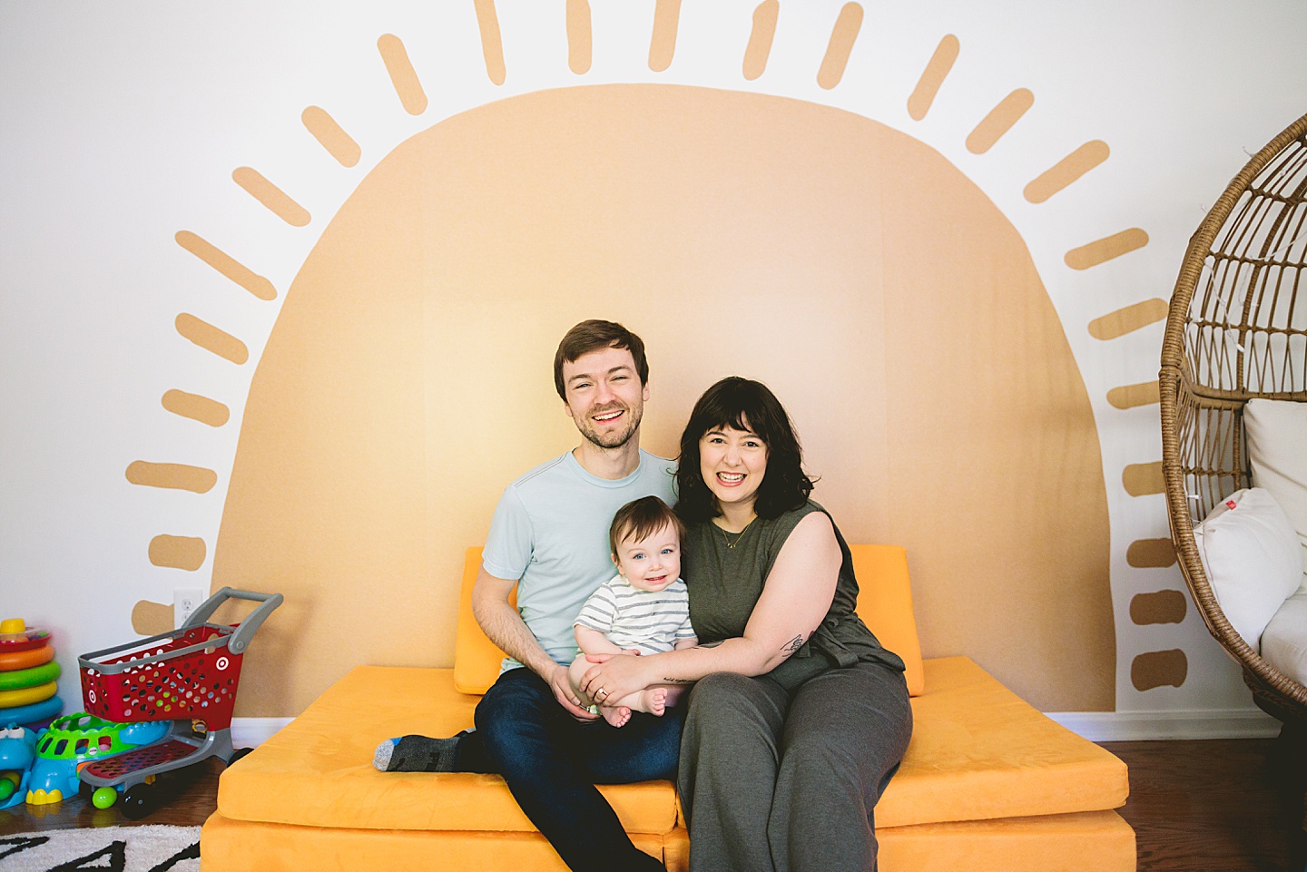 Family portrait in Cary NC of parents with toddler sitting in front of sun decal