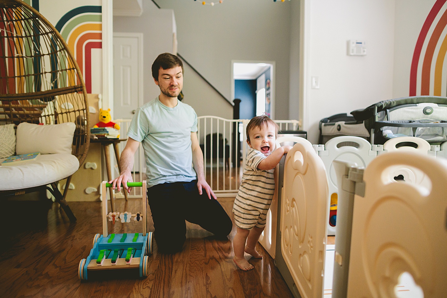 Baby standing and holding onto a playgate and laughing