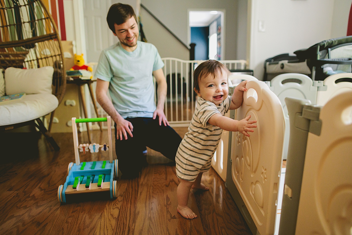 Baby standing and holding onto a playgate and laughing
