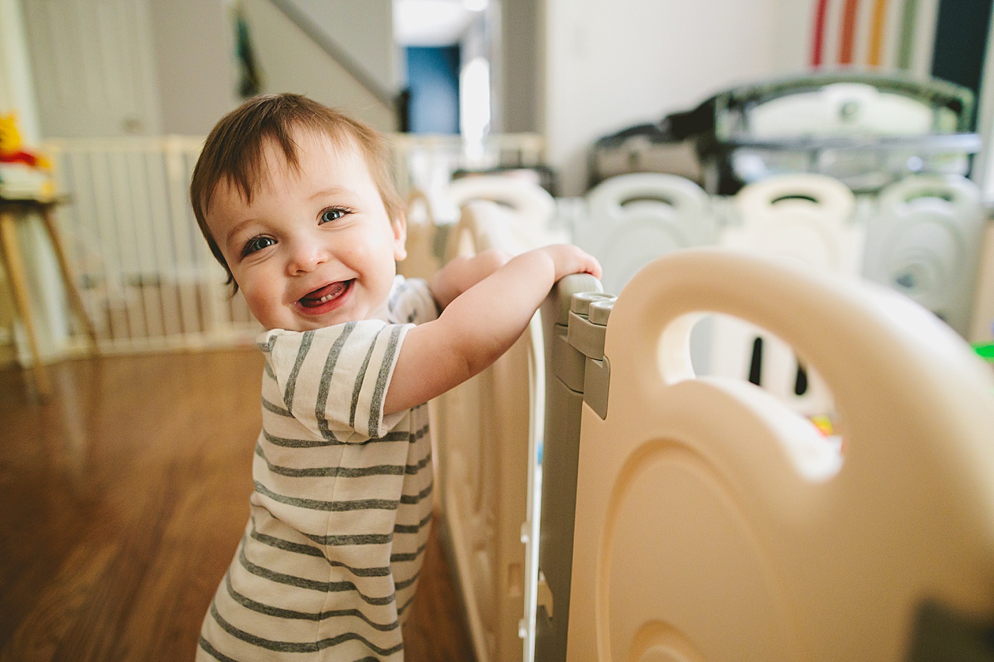 Baby standing and holding onto a playgate and laughing