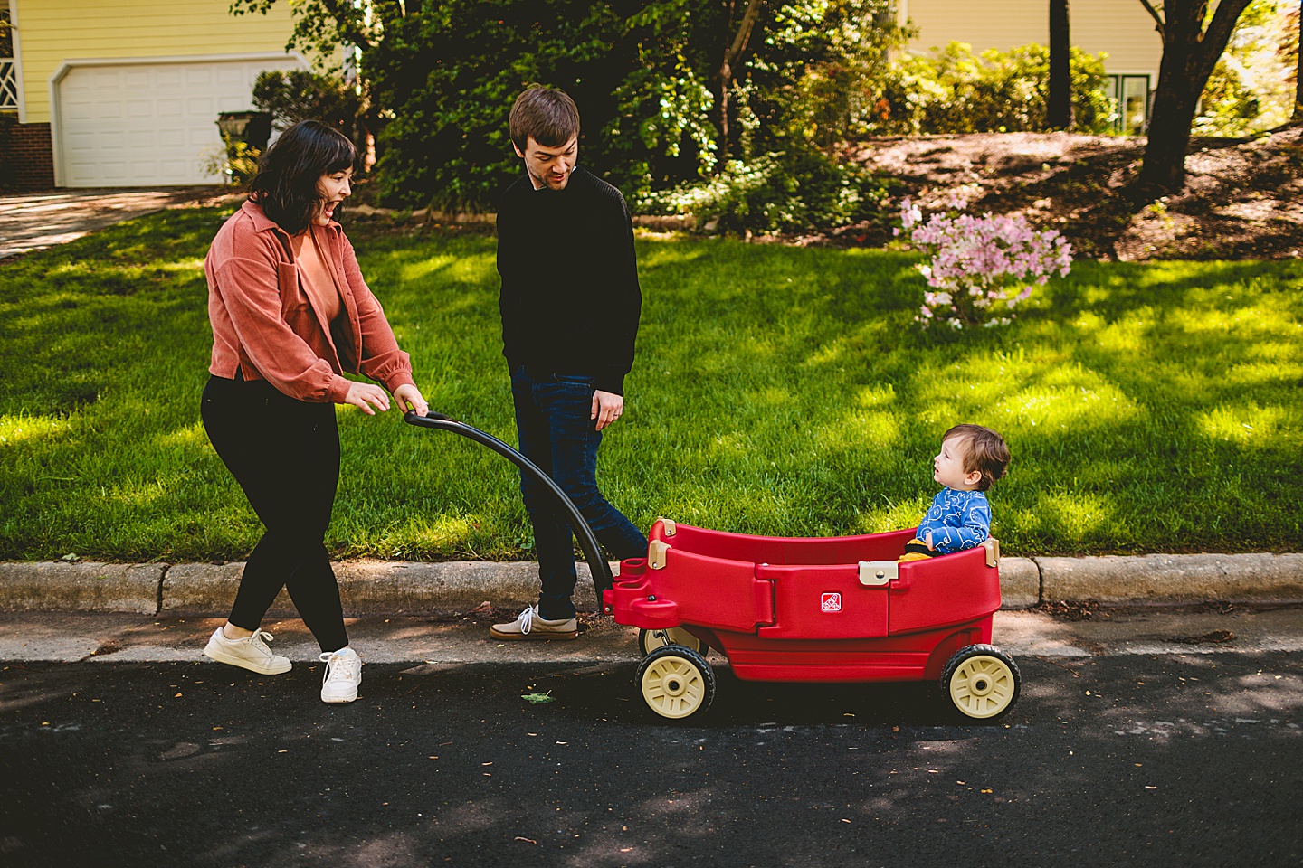 Parents pulling baby in red wagon down the street