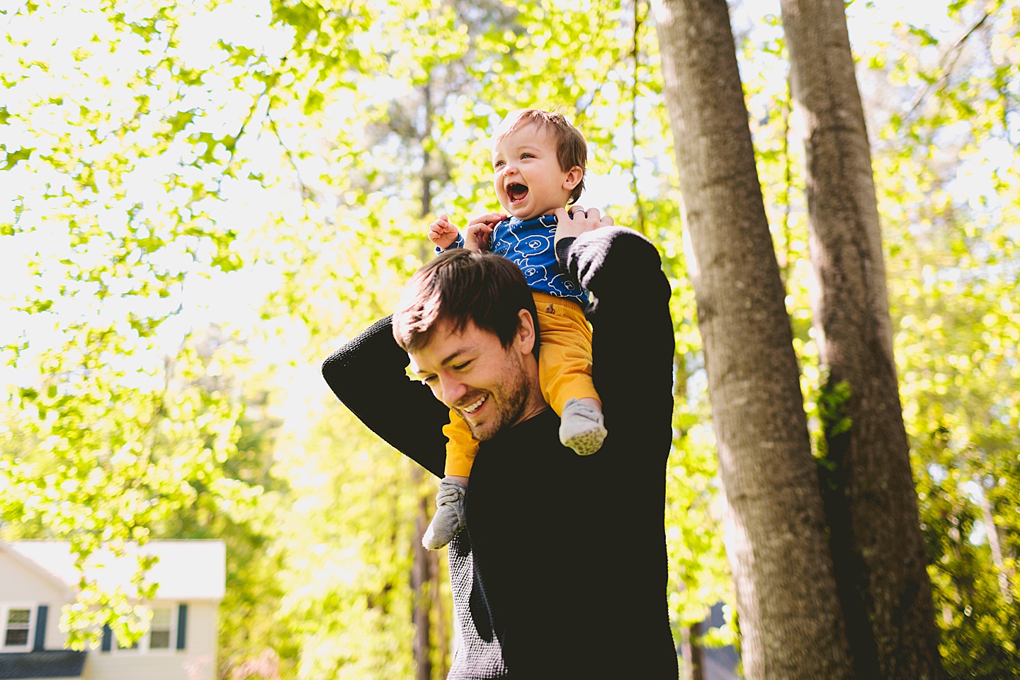 Dad holding laughing baby on his shoulders