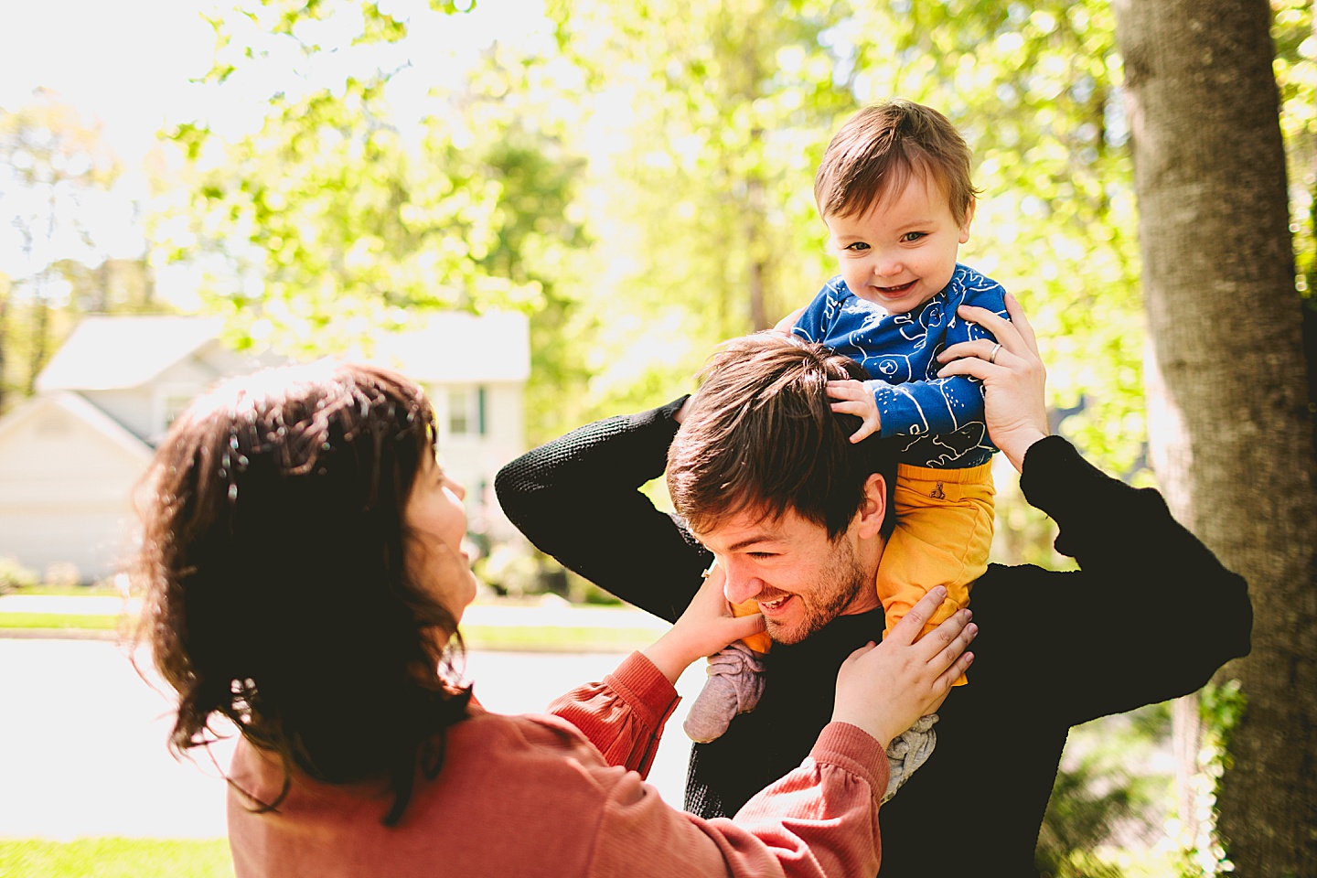 Dad holding laughing baby on his shoulders