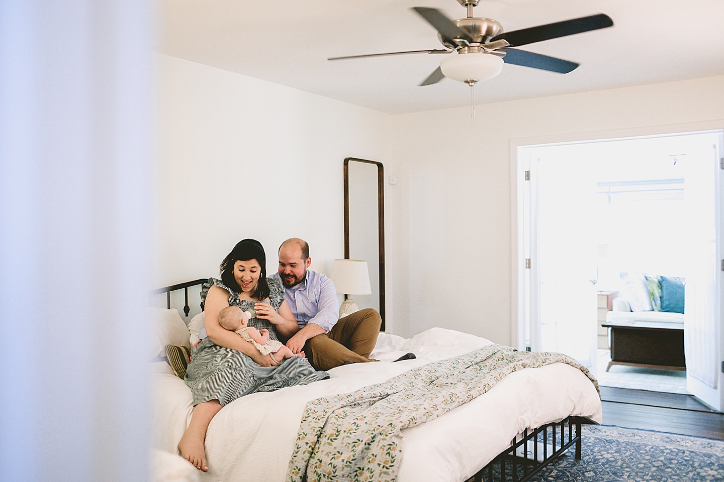 Mom feeding baby a bottle while sitting on bed 