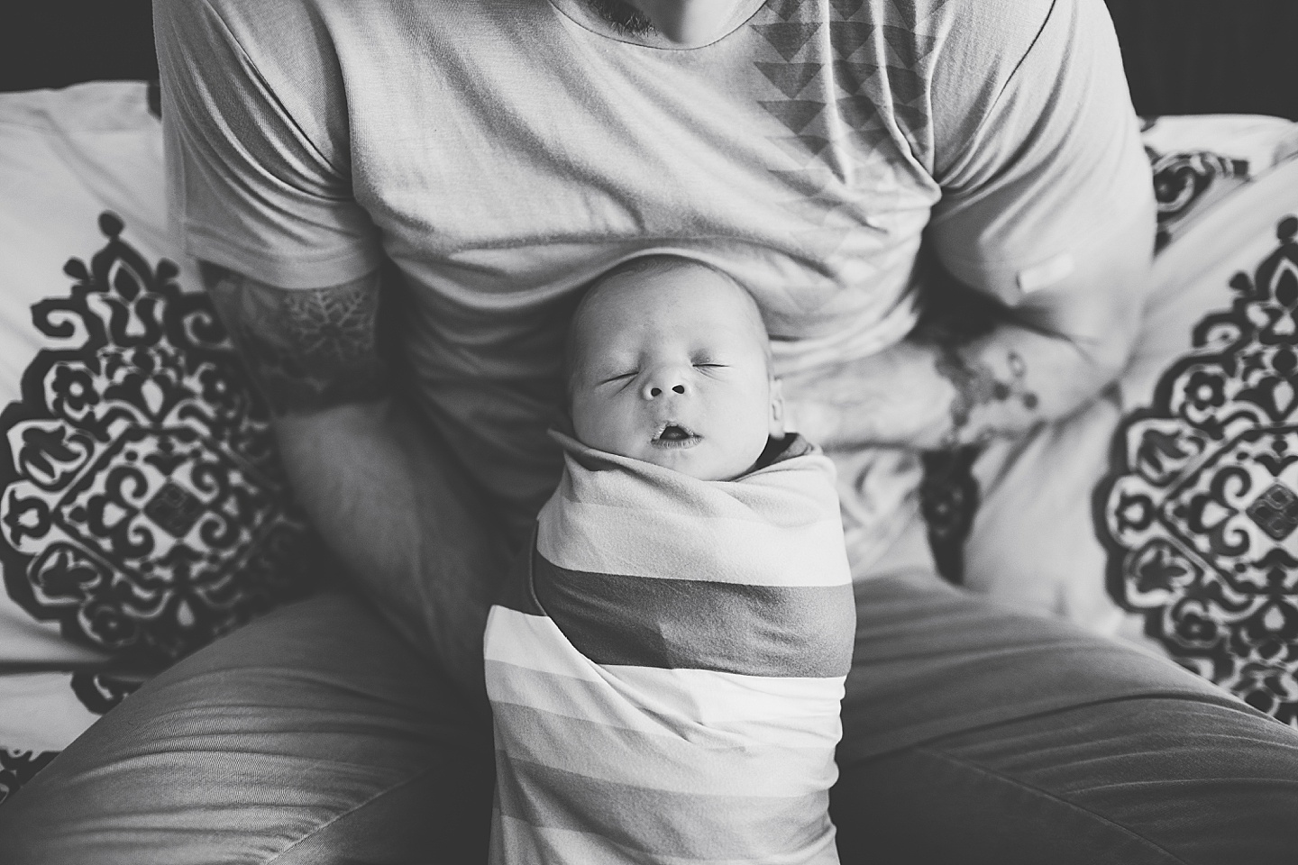 Black and white closeup of dad holding newborn baby