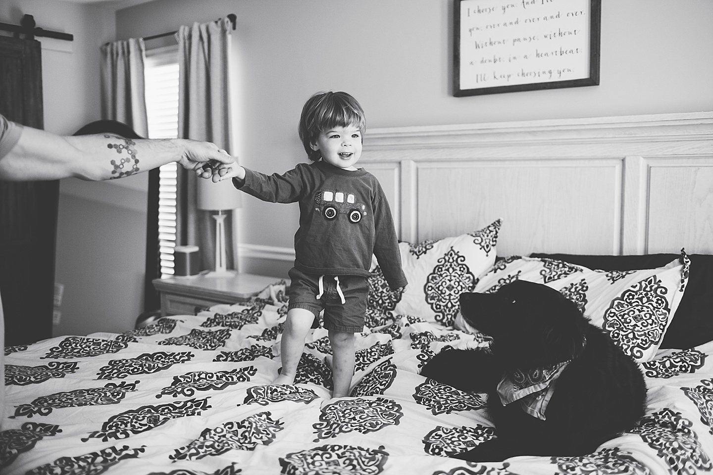 Black and white photo of toddler jumping on the bed