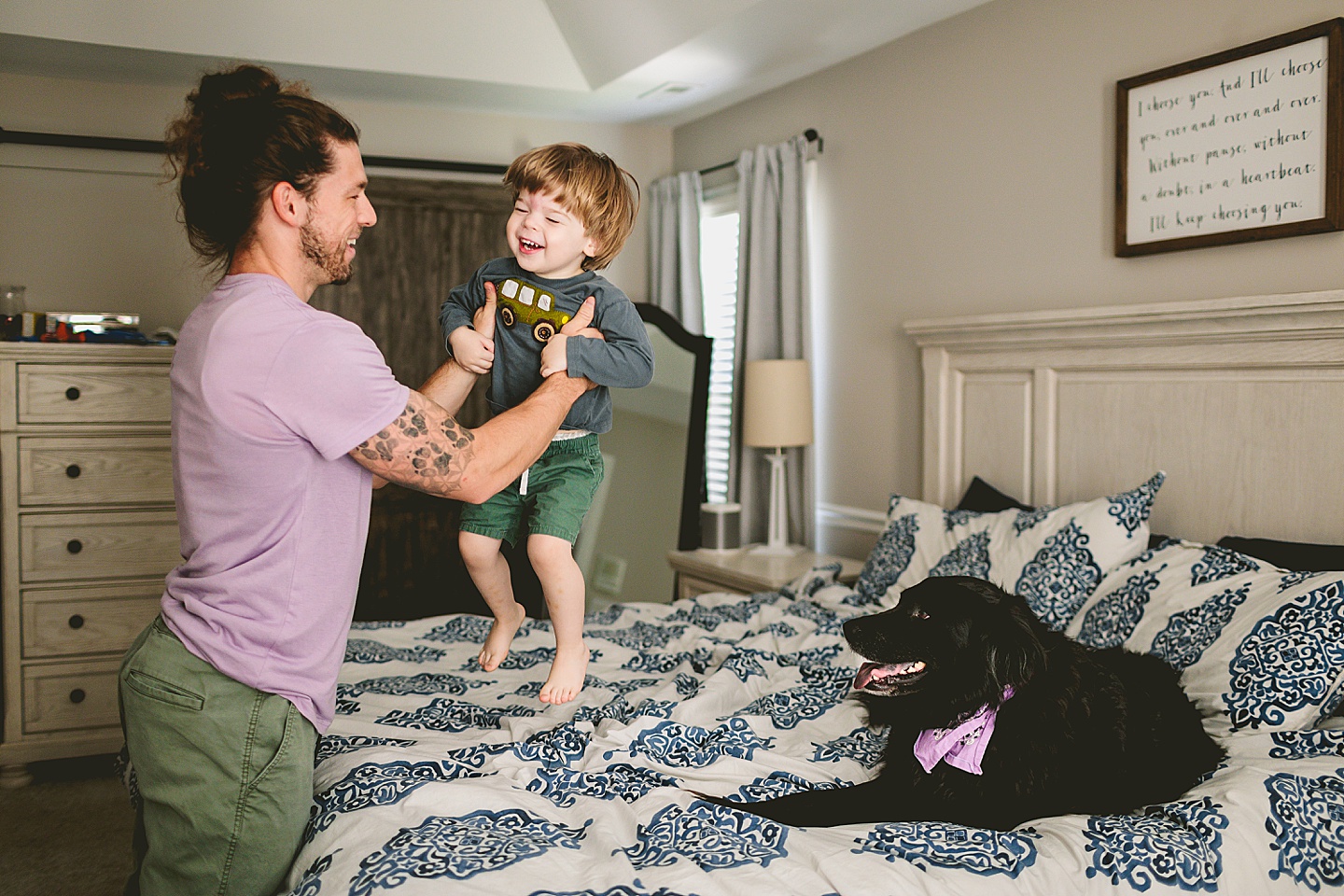 Toddler jumping on the bed with black dog