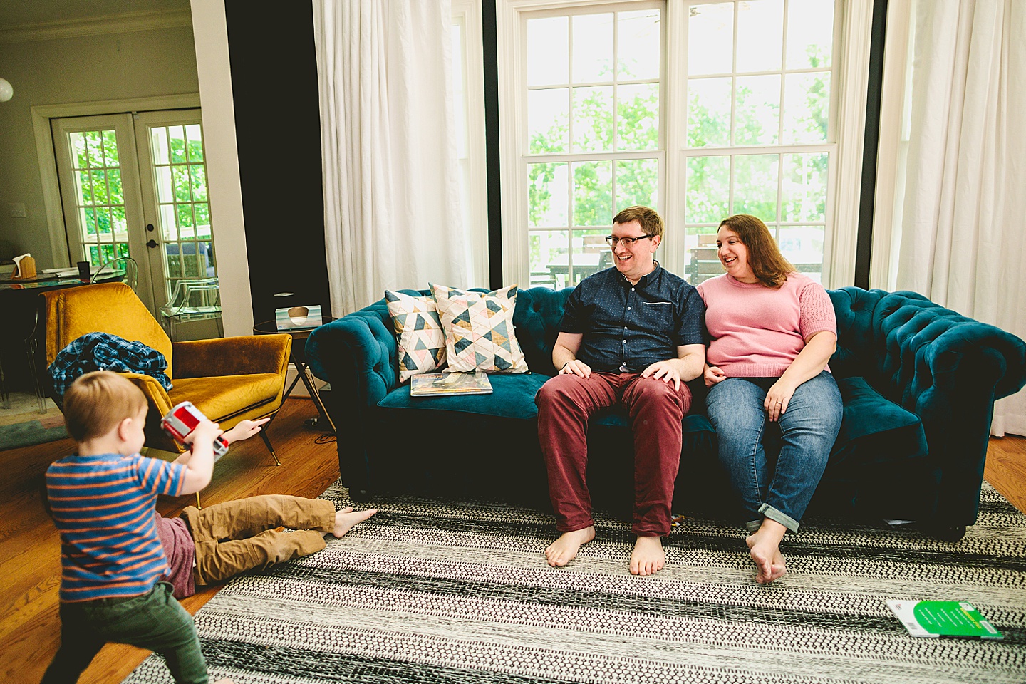 Parents laughing at kids playing in the living room during family pictures