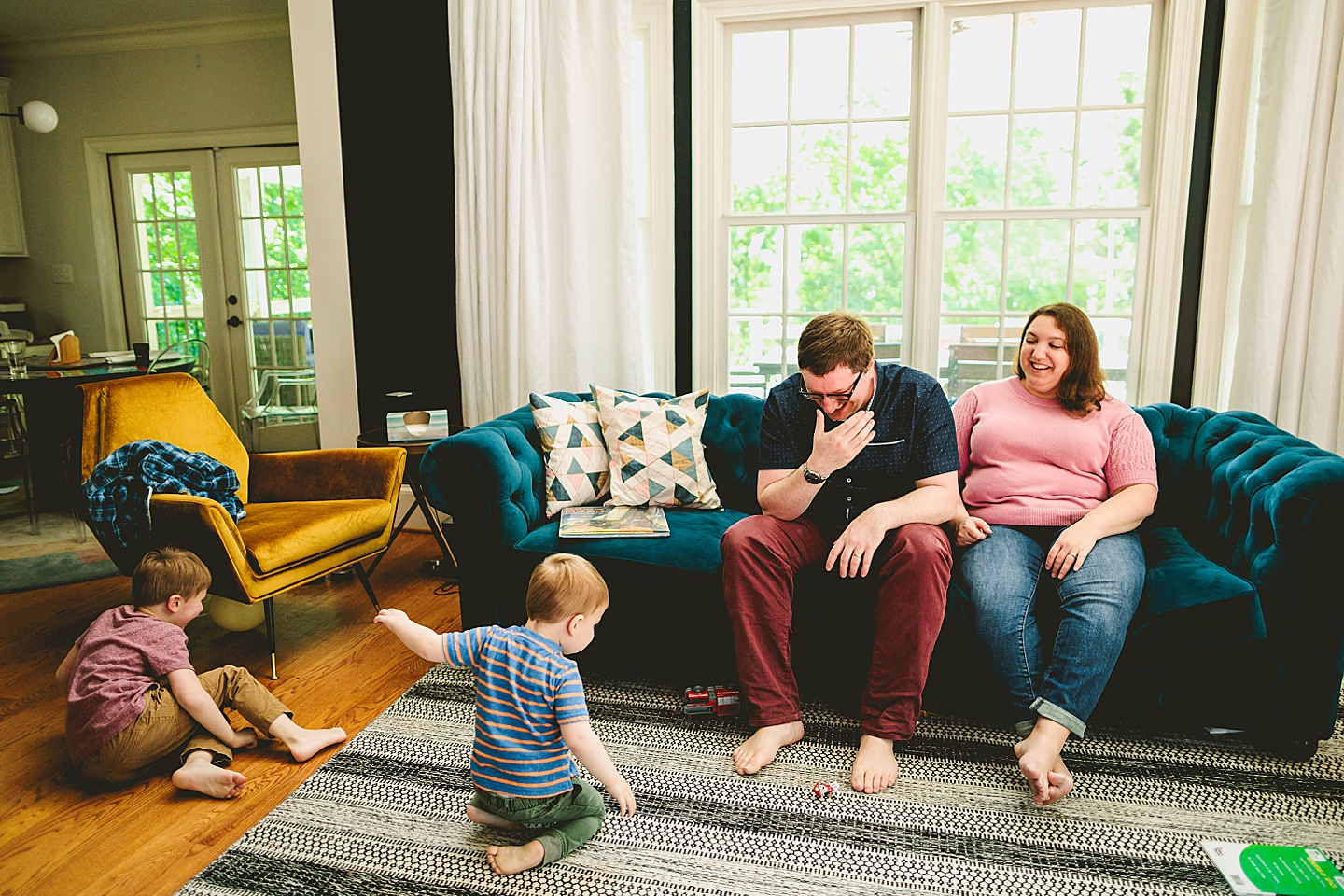 Parents laughing at kids playing in the living room during family pictures