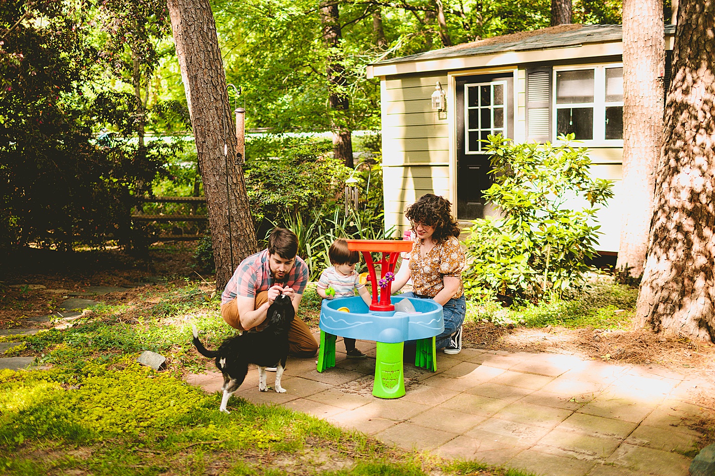 Parents playing outside at water table with toddler