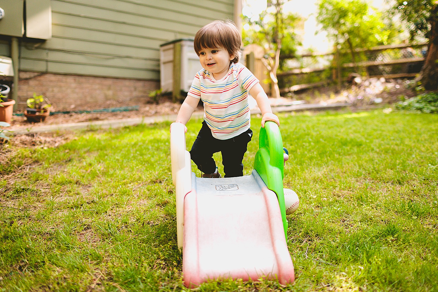 Toddler using tiny slide in yard