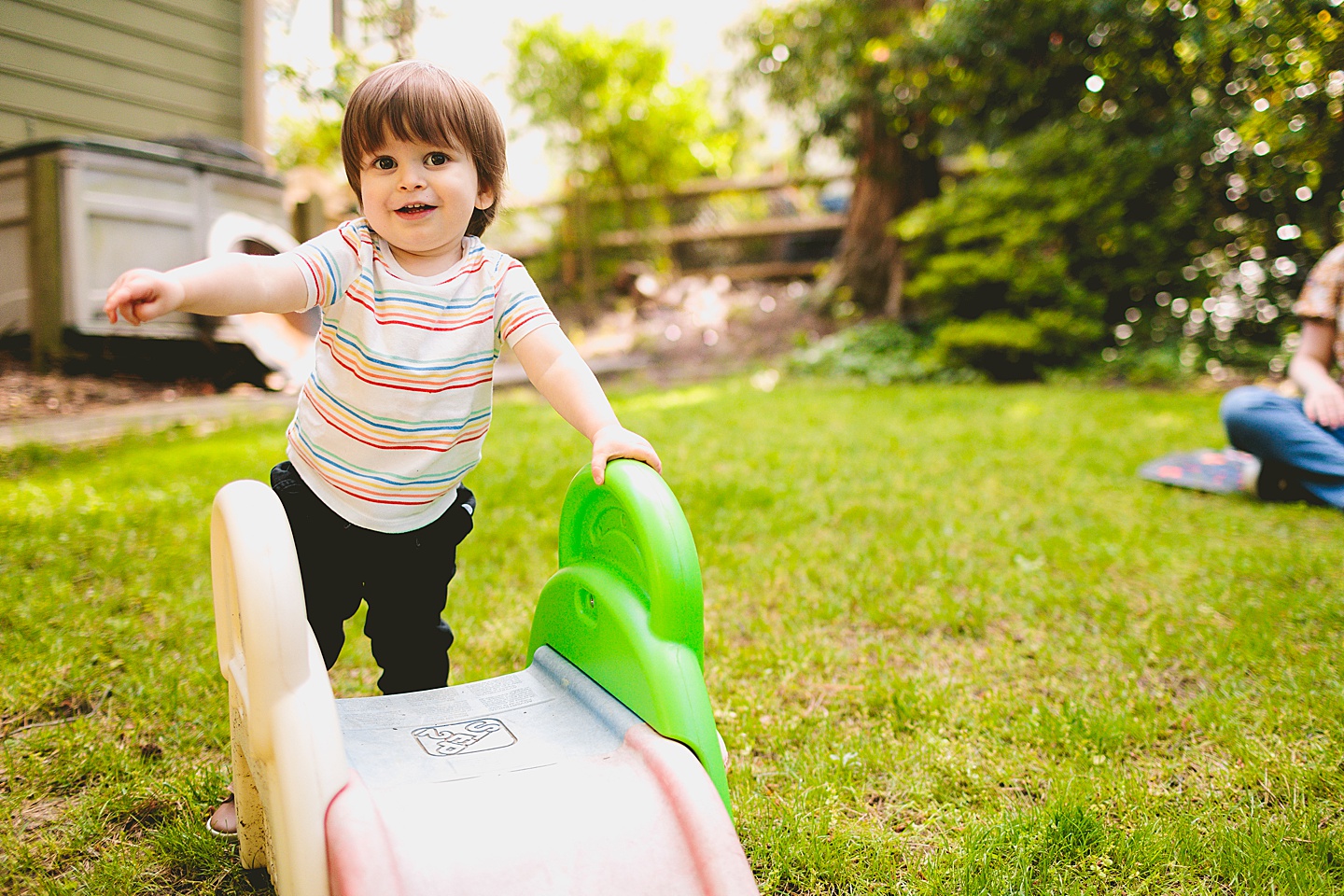 Toddler using tiny slide in yard