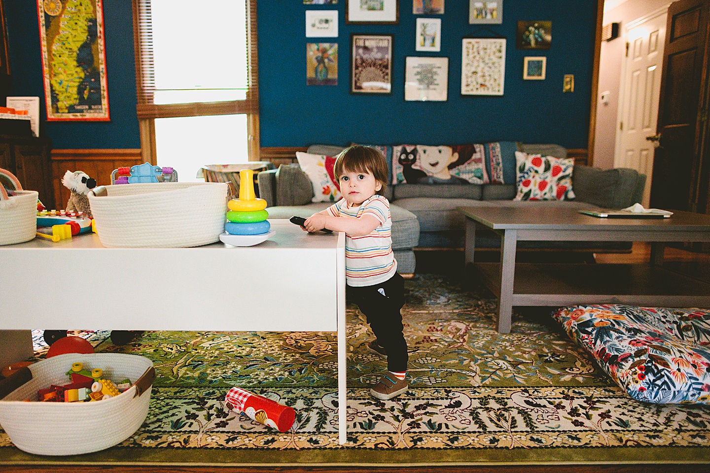 Toddler standing in living room holding remote control