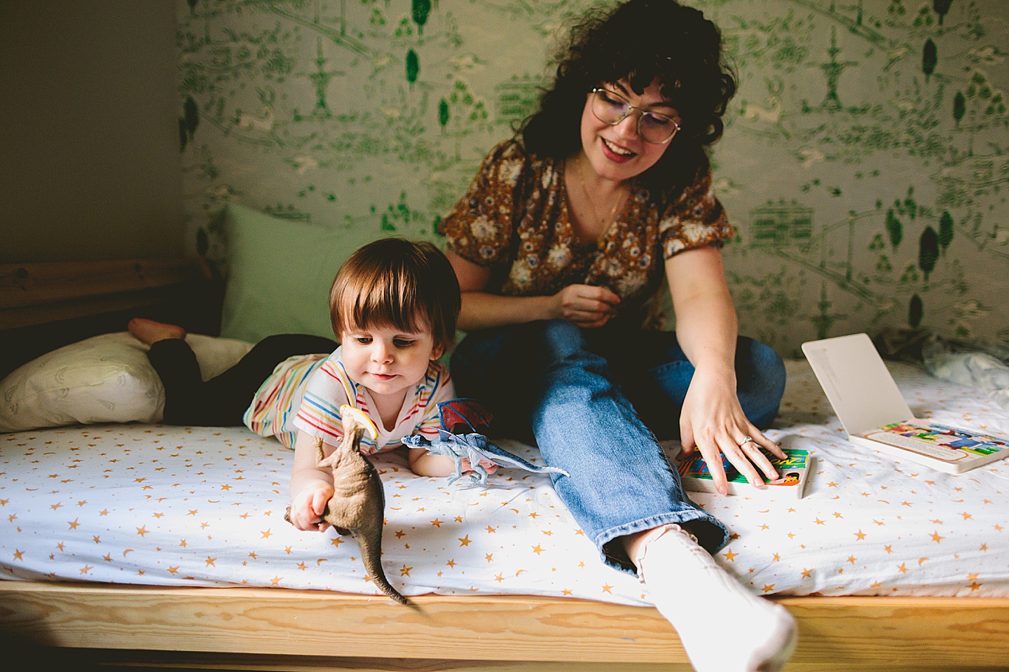 Kid plays with toy dinosaurs on bed