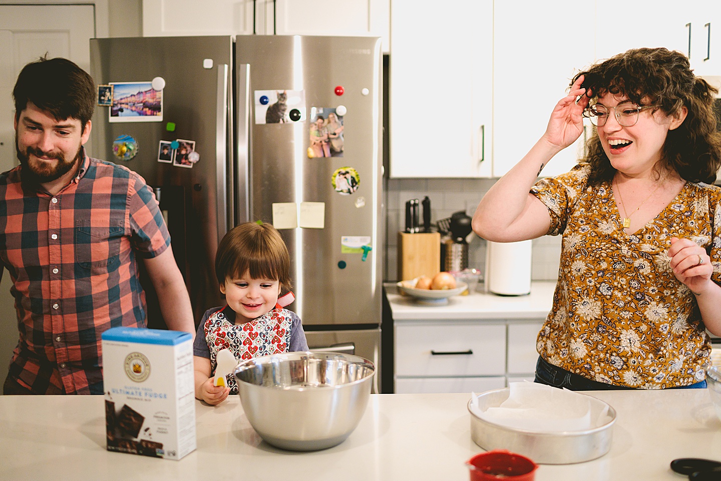 Parents laugh while making brownies with toddler