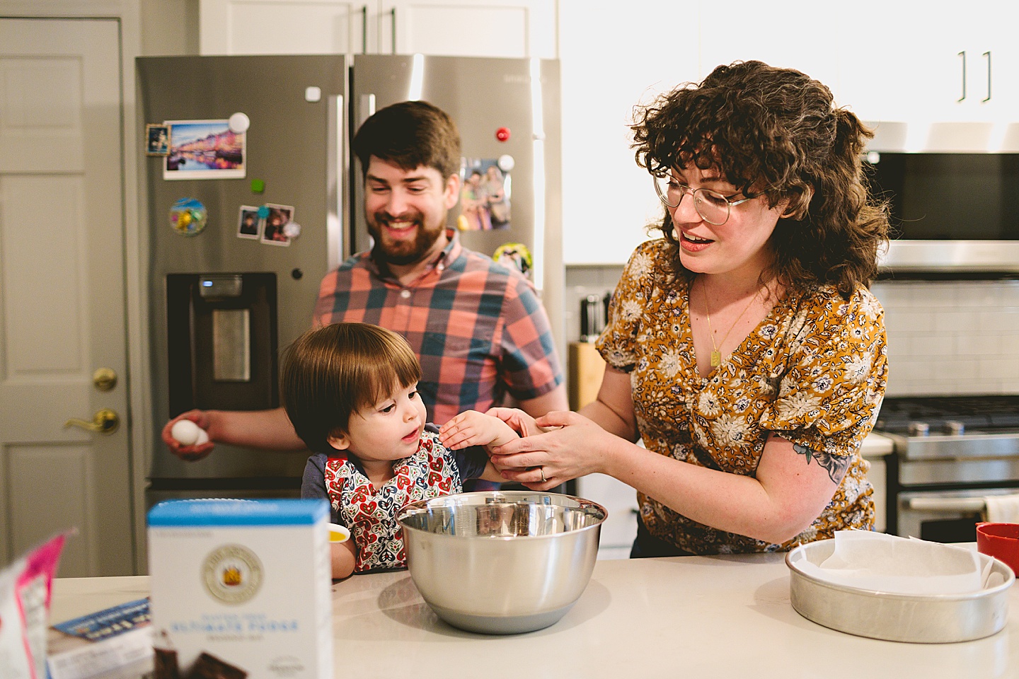 Parents laugh while making brownies with toddler