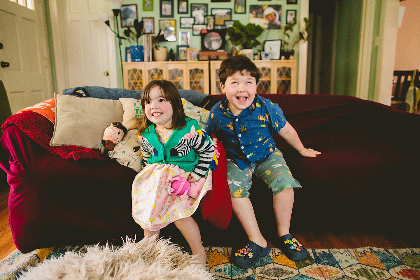 Siblings during at home family portraits in durham sit on couch