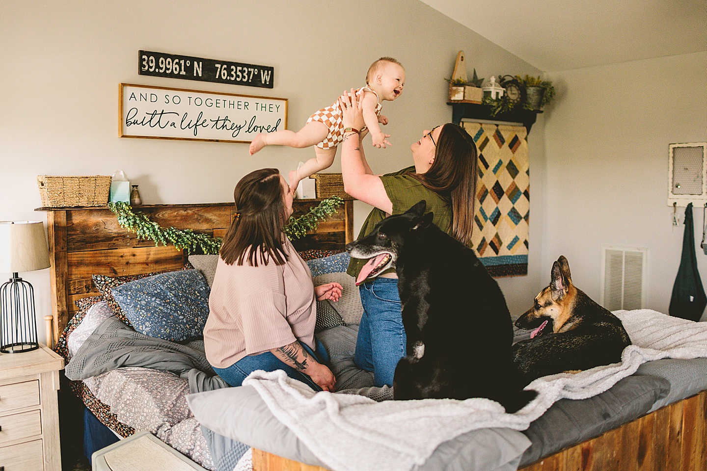 Parents holding laughing baby on bed