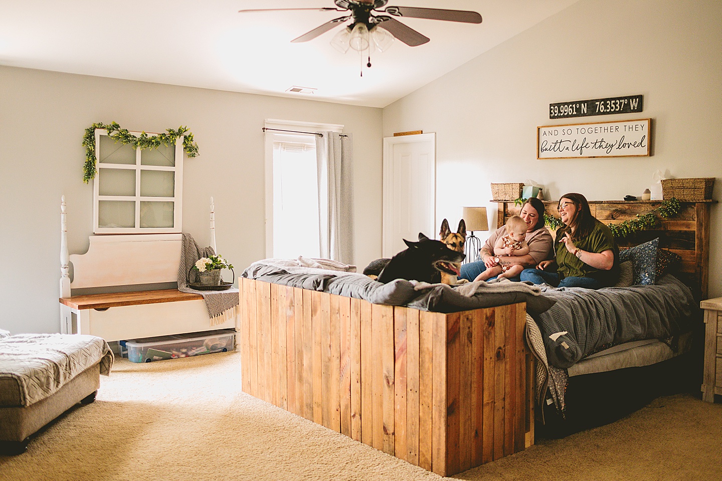 Women sitting on bed with baby and dogs