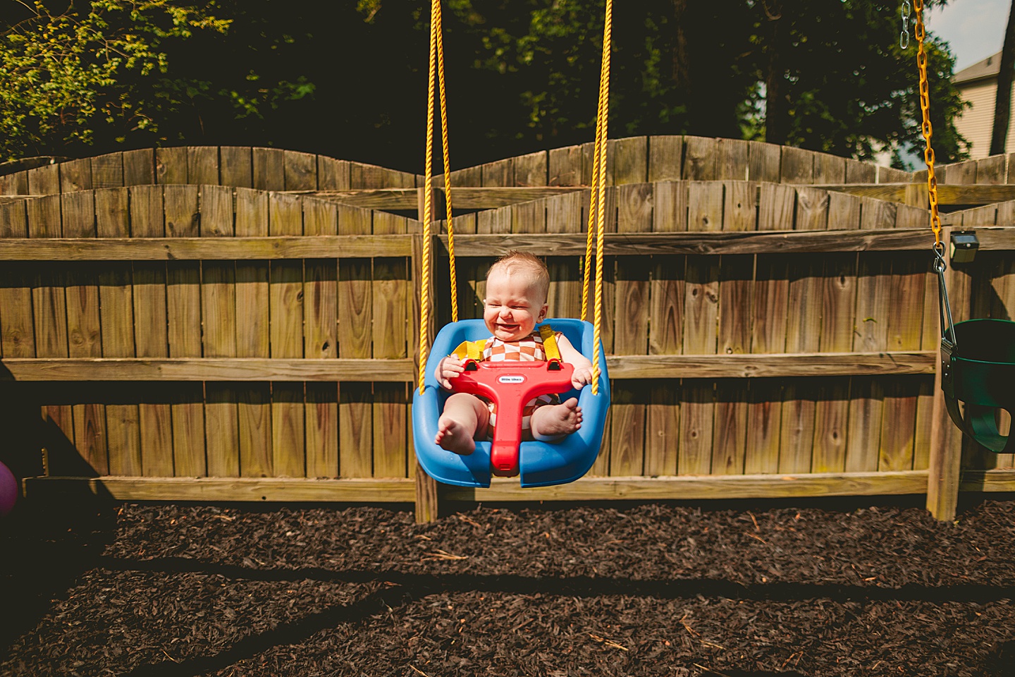 Child in a baby swing in back yard