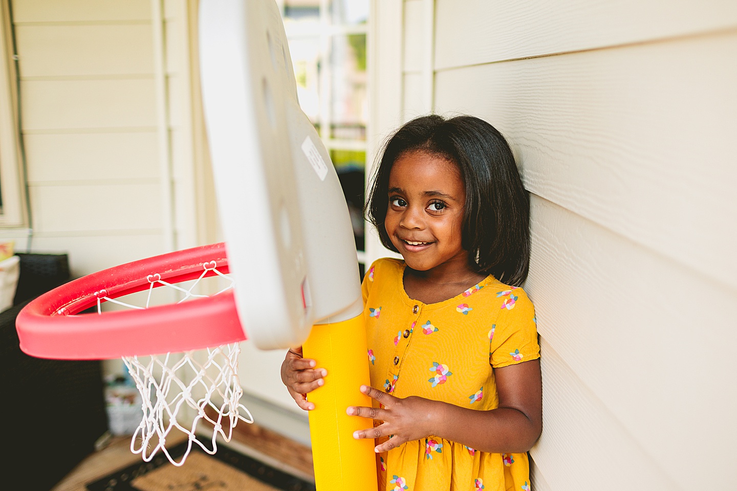 Girl standing by basketball hoop and smiling