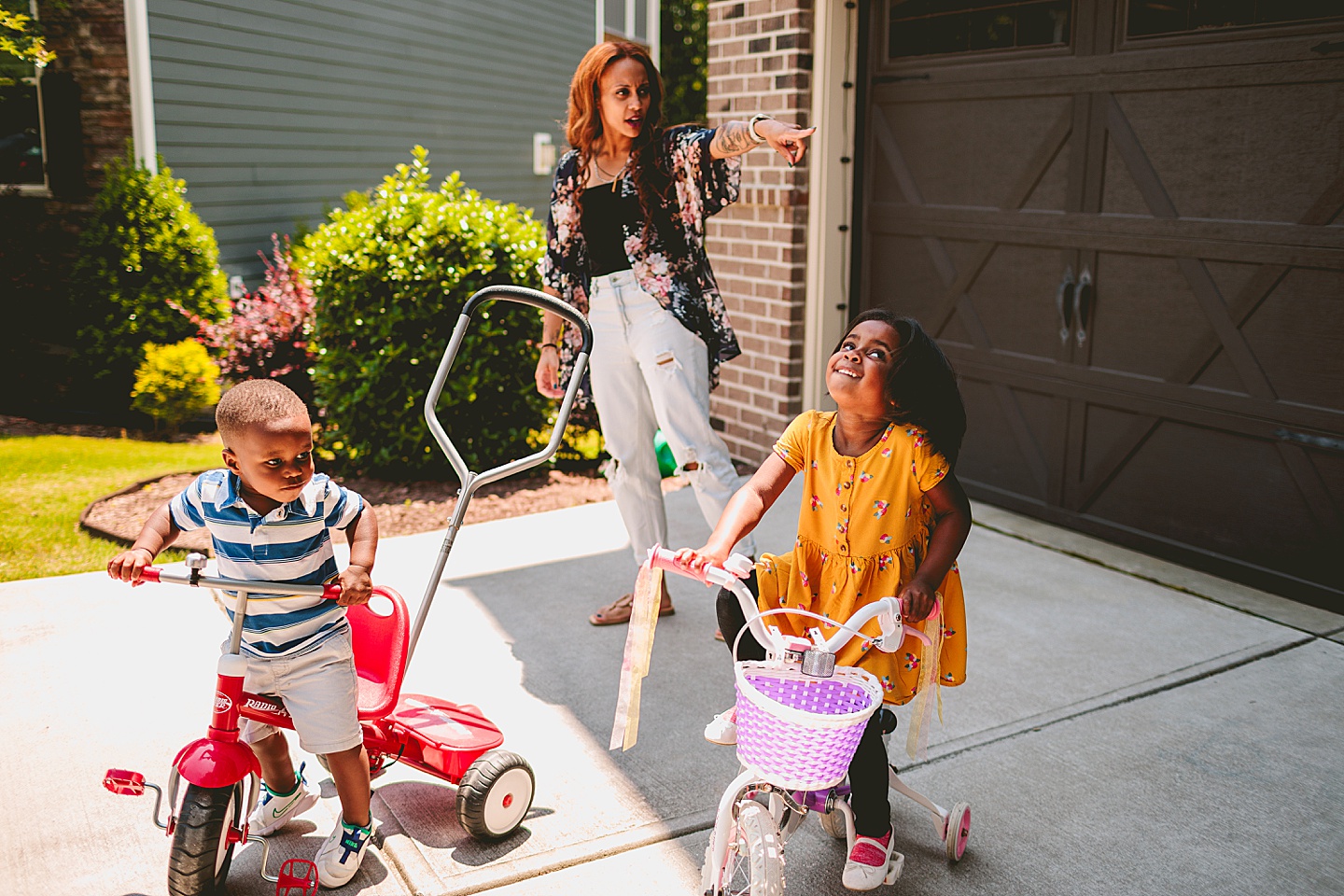 Kids riding bikes with their mom outside in the driveway