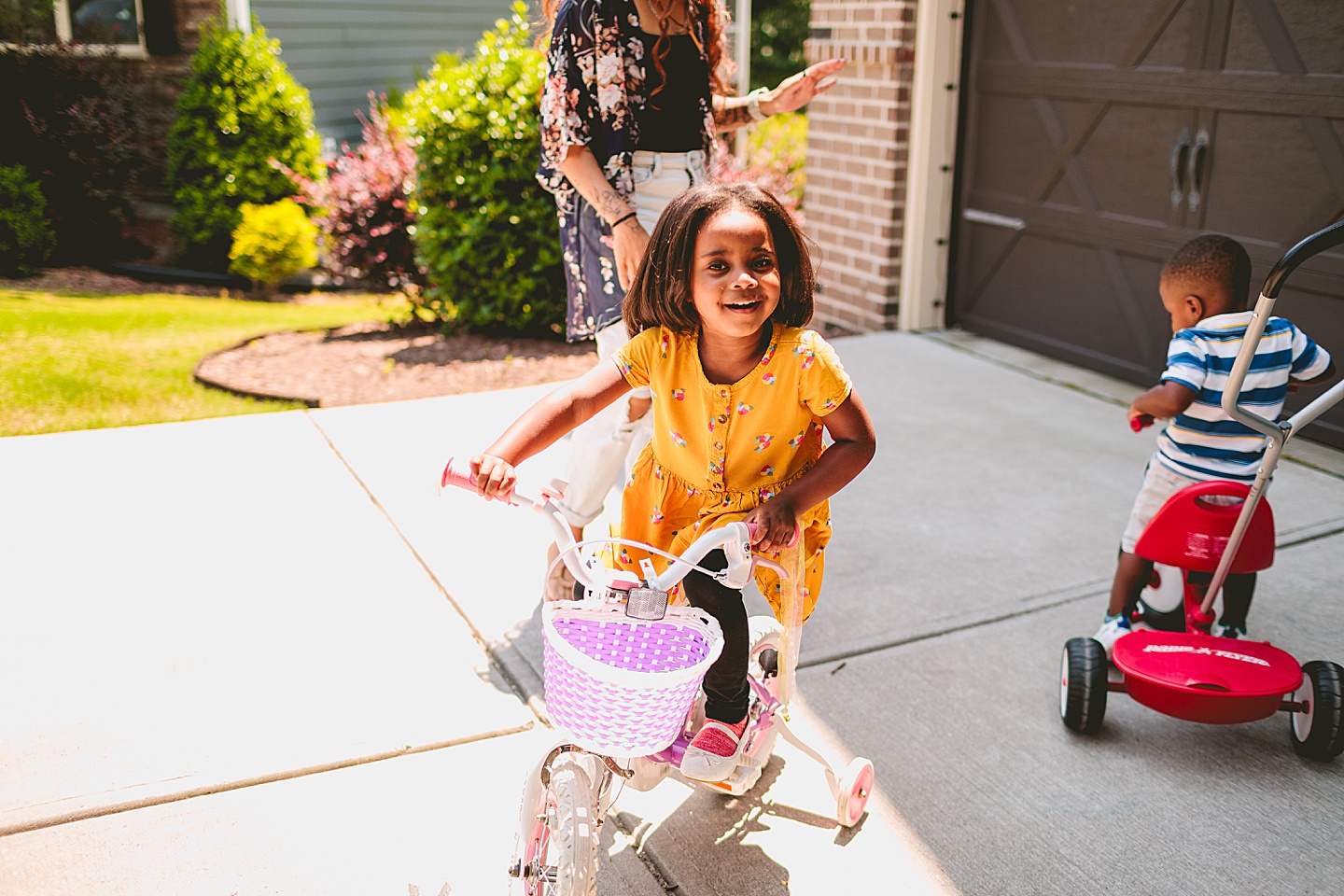 Kids riding bikes with their mom outside in the driveway