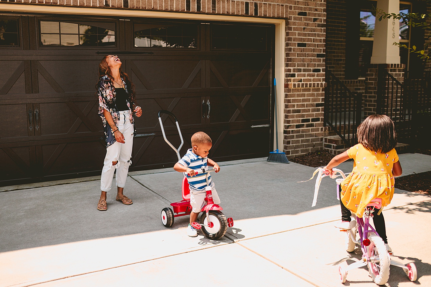 Kids riding bikes with their mom outside in the driveway