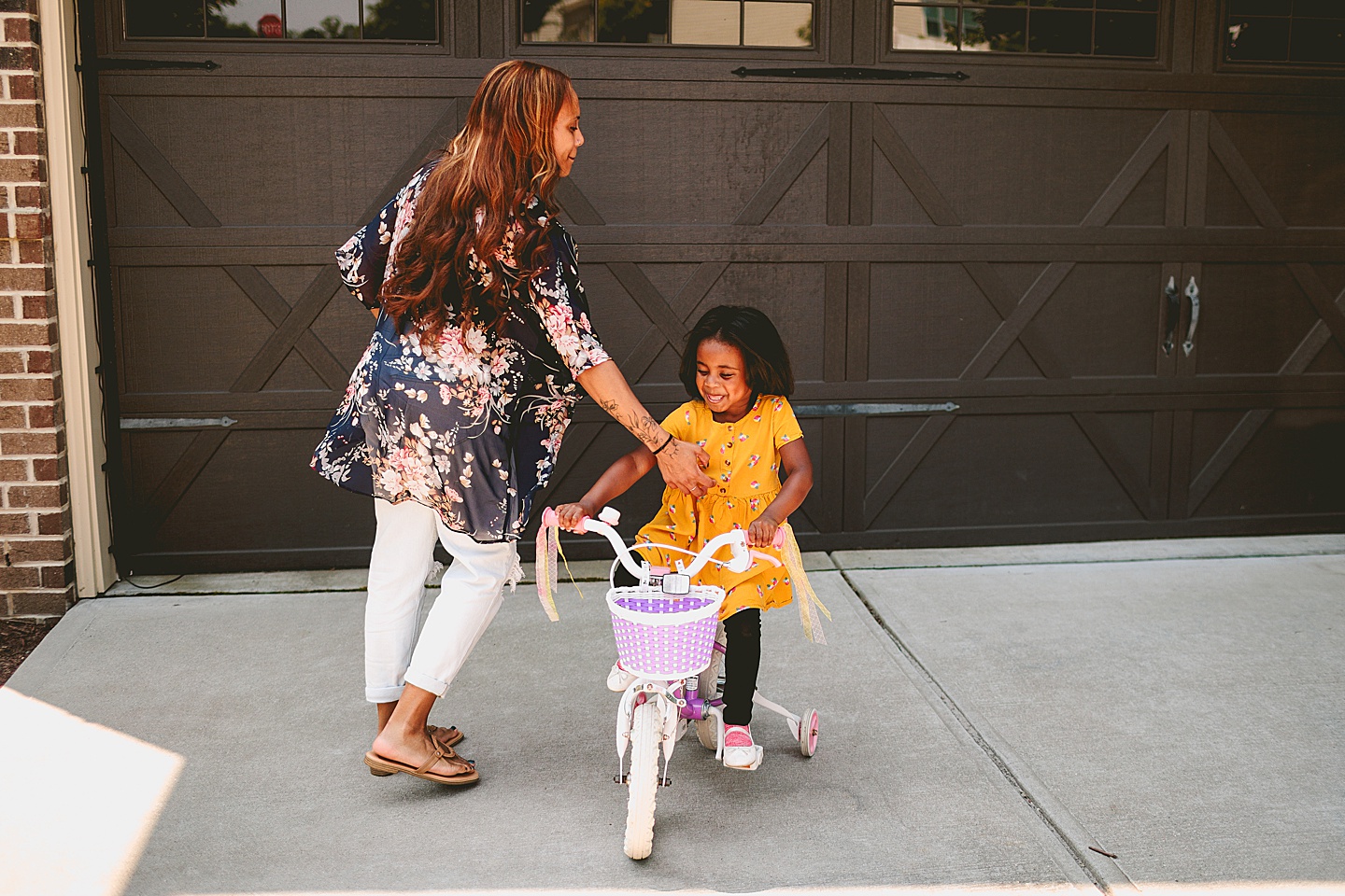 Kids riding bikes with their mom outside in the driveway