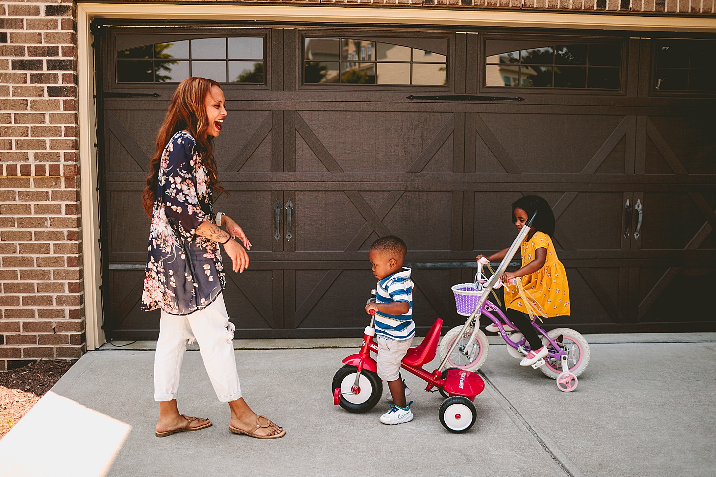 Kids riding bikes with their mom outside in the driveway