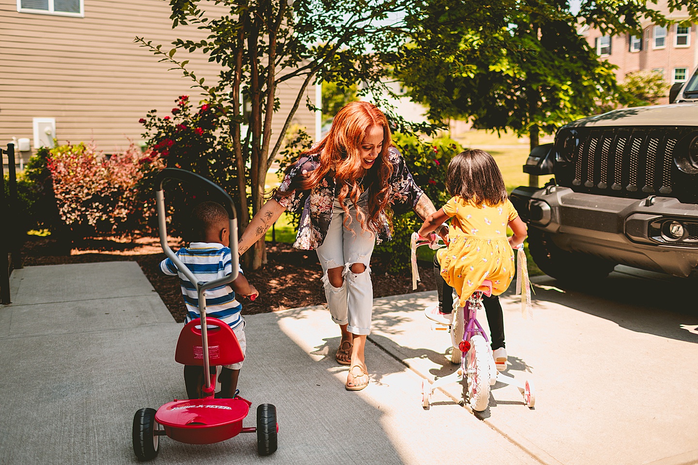 Kids riding bikes with their mom outside in the driveway