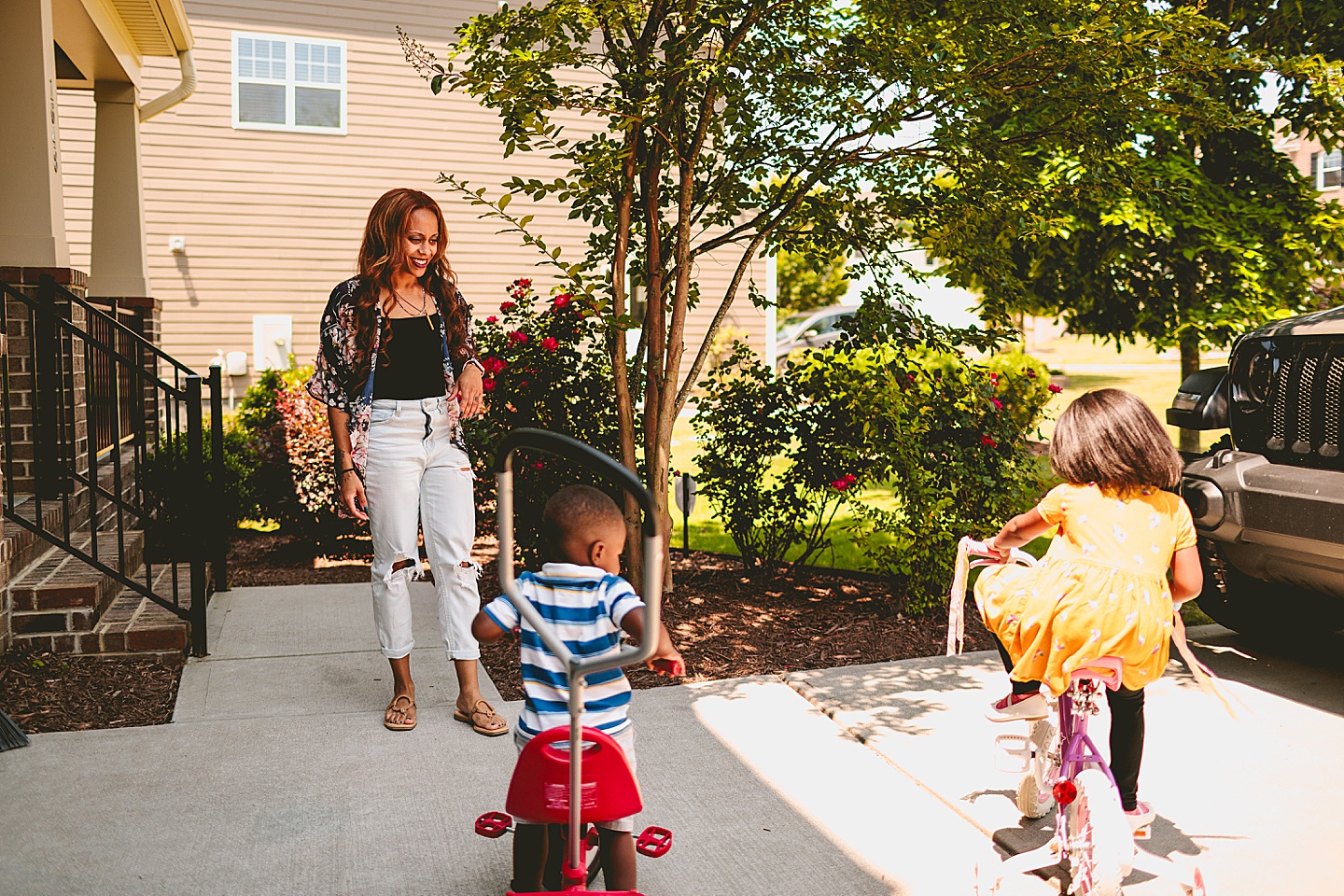 Kids riding bikes with their mom outside in the driveway