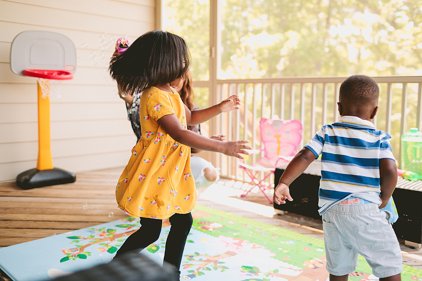 Kids running through bubbles outside on deck in Cary