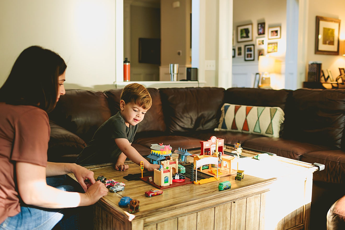 Kid playing with set of cars in the living room with his mom
