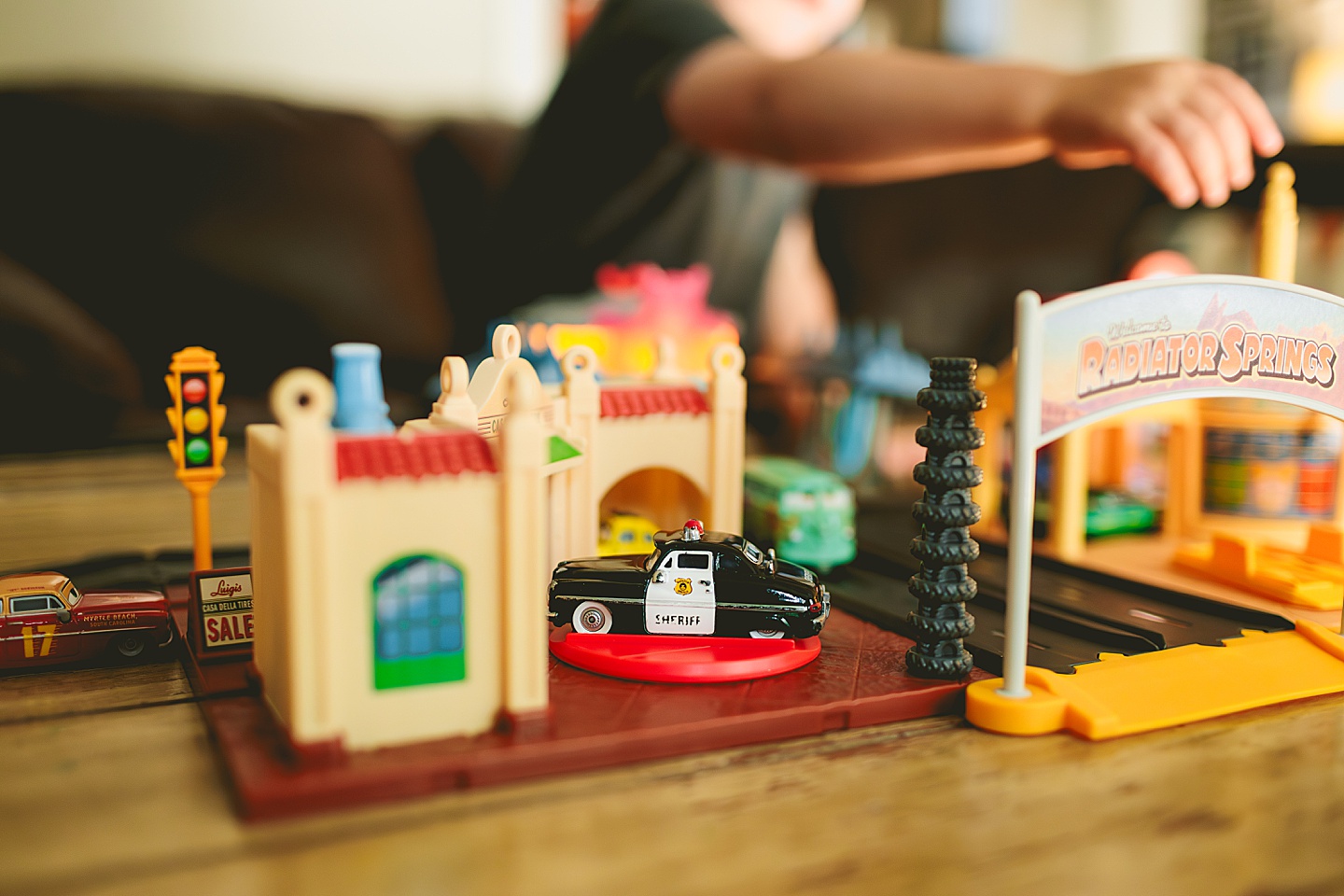 Kid playing with set of cars in the living room with his mom