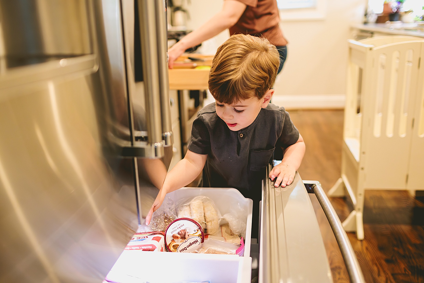 Toddler looking through the freezer for ice cream