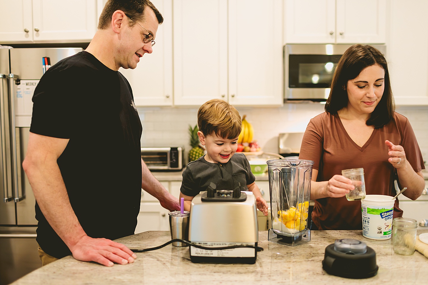 Kid making a smoothie with his parents in the kitchen