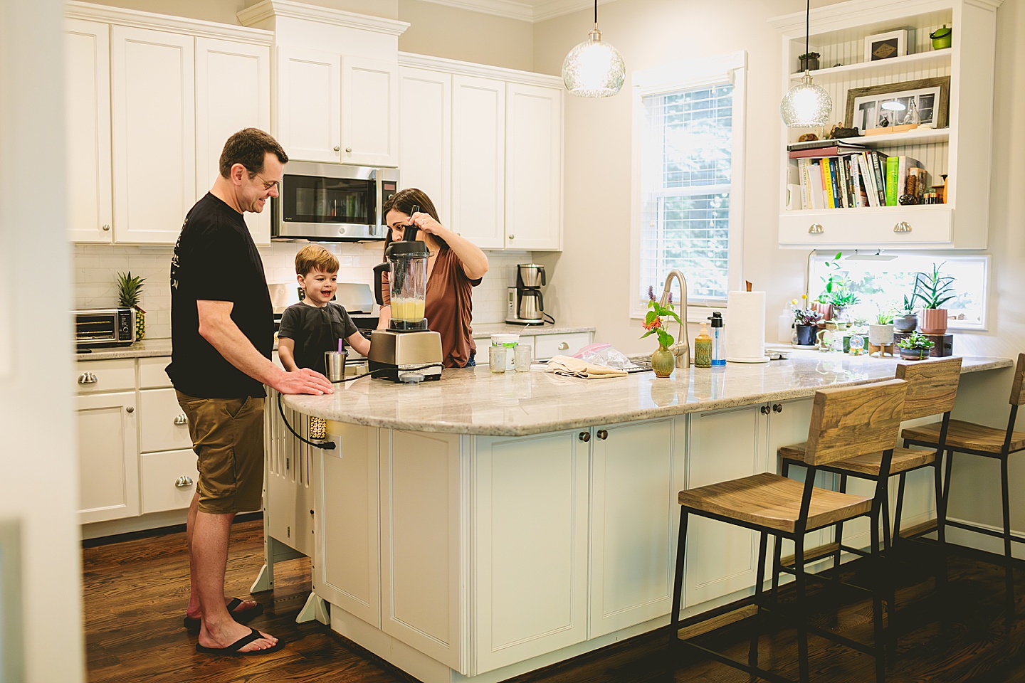 Kid making a smoothie with his parents in the kitchen