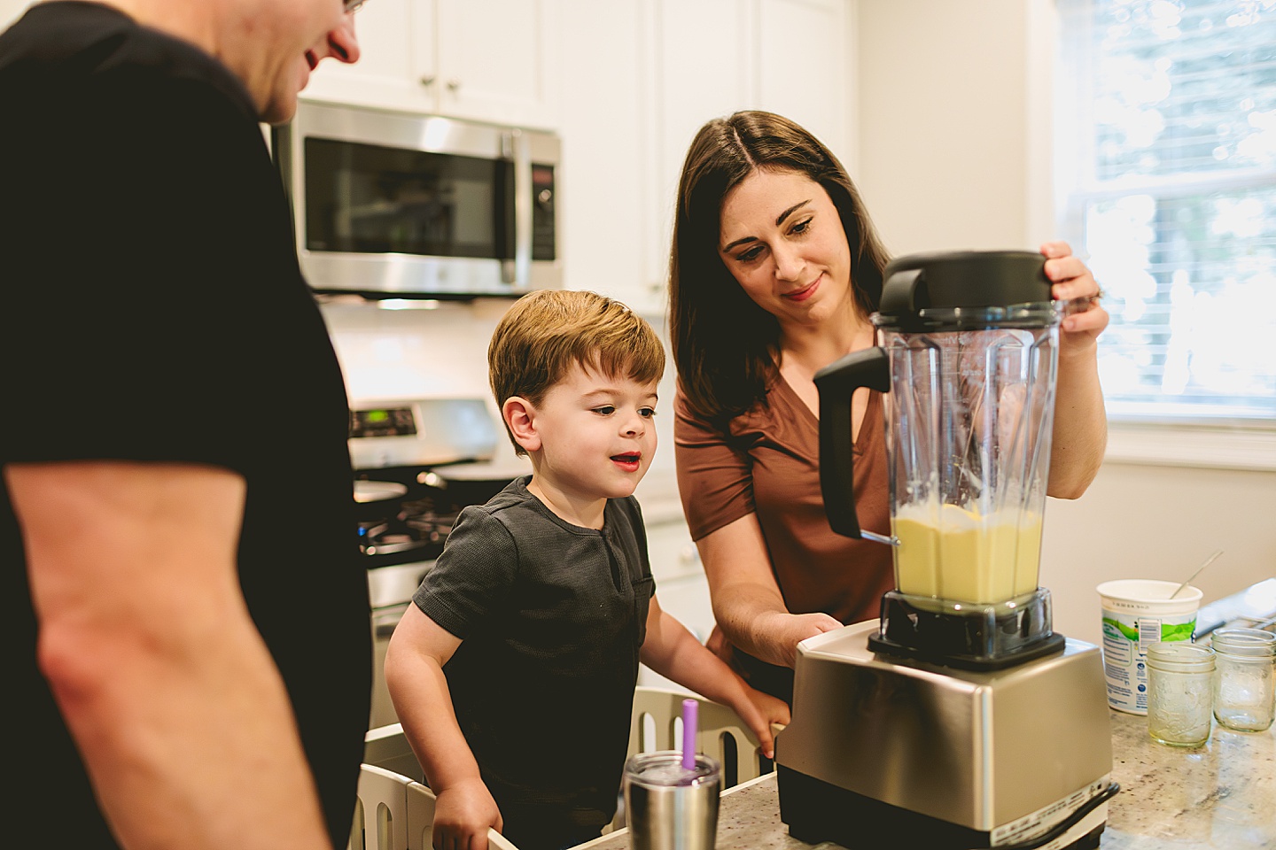 Kid making a smoothie with his parents in the kitchen