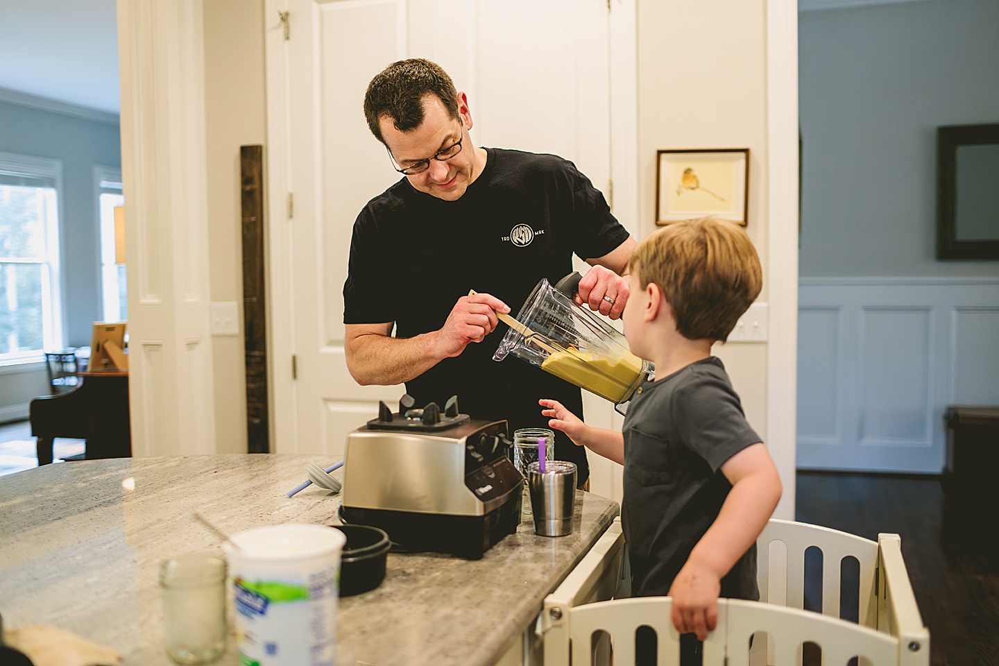 Kid making a smoothie with his parents in the kitchen