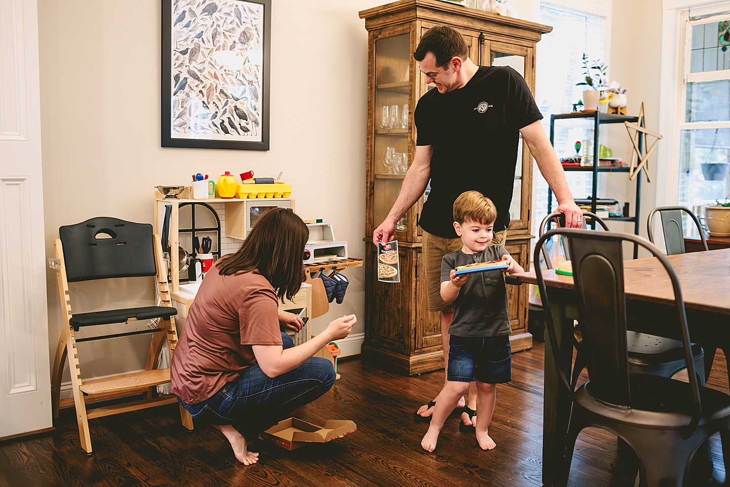 Toddler using play kitchen to make pizza for his family