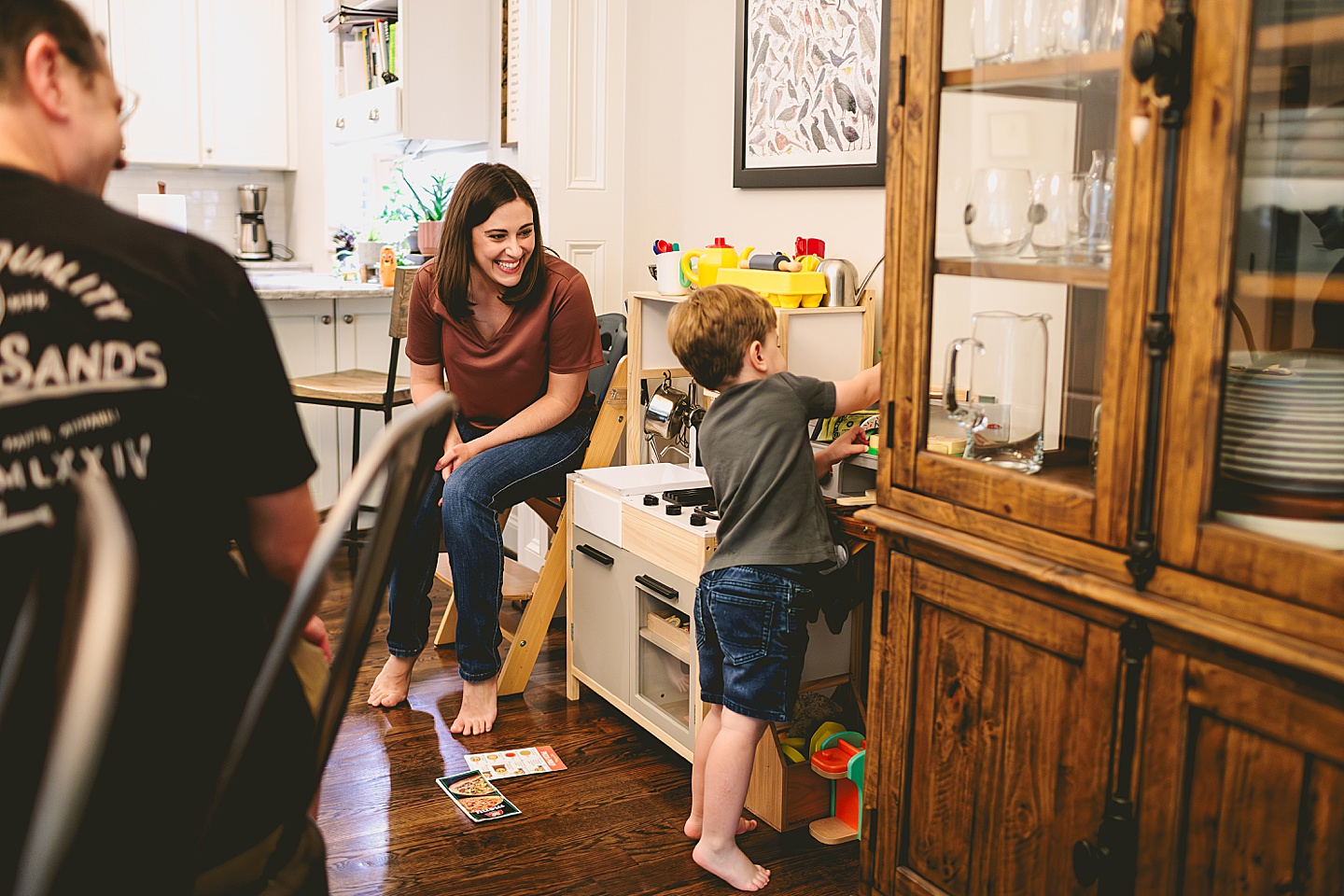 Toddler using play kitchen to make pizza for his family