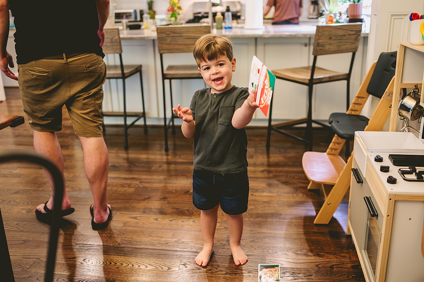 Toddler using play kitchen to make pizza for his family