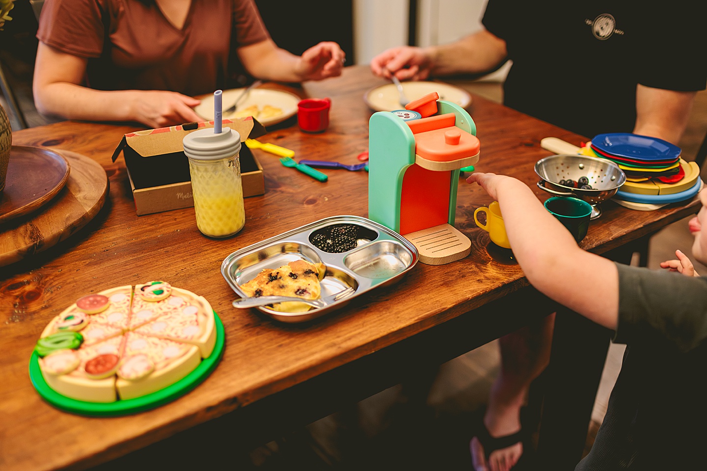 Toddler using play kitchen to make pizza for his family