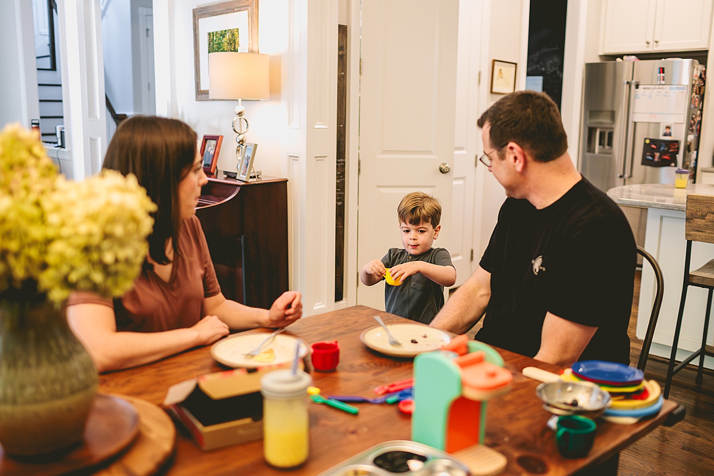 Toddler using play kitchen to make pizza for his family