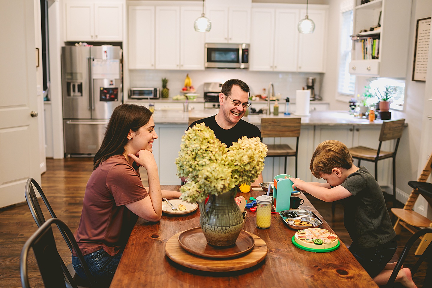 Toddler using play kitchen to make pizza for his family